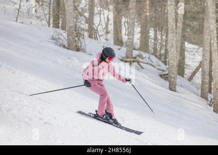 Ski alpin en descente.Femme en ski alpin s'amusant sur les pistes par une journée enneigée - sports et activités d'hiver.Vêtements de ski frais, lunettes de protection Banque D'Images