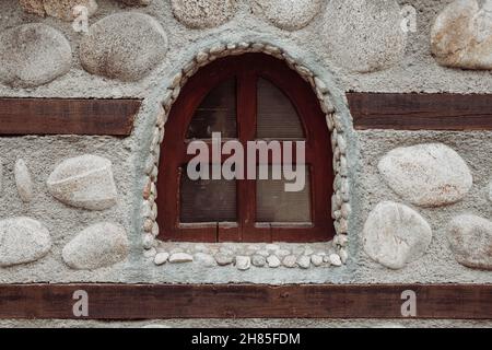 Gros plan d'une fenêtre en bois sombre sur une vieille maison en pierre.Maison en pierre traditionnelle des Balkans.Belle architecture.Photo de haute qualité Banque D'Images