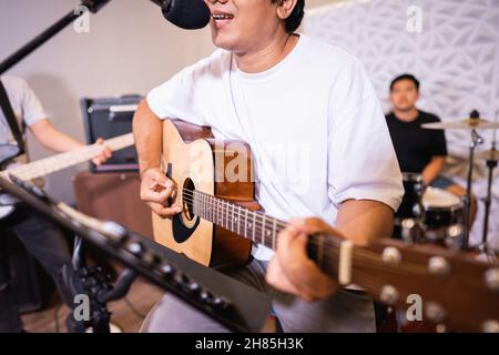 gros plan d'un chanteur masculin chantant tout en jouant une guitare acoustique Banque D'Images