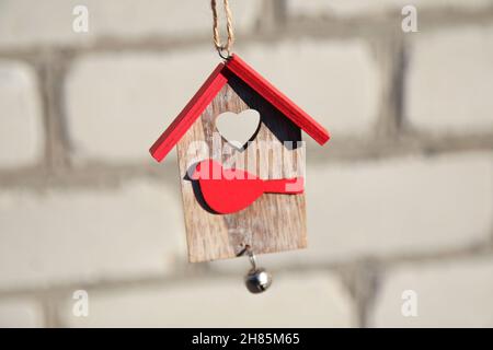 Maison de jouets en bois de Noël avec toit rouge et oiseau sur mur en brique blanche.Concept de décoration de Noël.Petite maison.Restez à la maison.Modèle pour plus de design. Banque D'Images