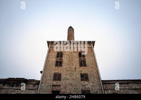 Image d'un complexe industriel abandonné de la révolution industrielle avec une cheminée en brique, et une ancienne usine et un entrepôt qui était autrefois partie o Banque D'Images