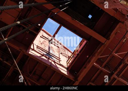 Ciel bleu vu par une ouverture rectangulaire dans le toit d'une grande structure industrielle en acier, aspect horizontal Banque D'Images