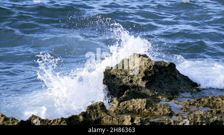 De petites vagues frappent et éclabousse le rivage de la mer.Action.Vagues qui frappent le rock.Éclaboussures de vagues sur de petites roches. Banque D'Images