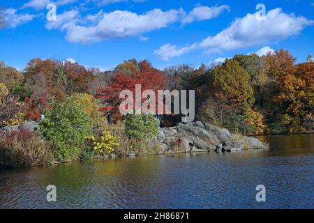 New York, Central Park Lake avec rochers et feuillage d'automne sur les arbres Banque D'Images