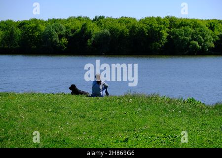 Une fille avec un chien dans un champ près de l'eau.Photo de haute qualité Banque D'Images