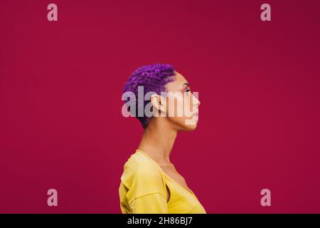 Cheveux violets à bascule.SideView d'une jeune femme à la mode portant des cheveux violets dans un studio.Jeune femme élégante qui a l'air confiante en se tenant de nouveau debout Banque D'Images