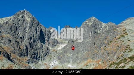 Un téléphérique rouge sur son chemin de Skalnate pleso à Lomnicky pic.Télécabine rouge se déplaçant jusqu'au sommet de Lomnica dans les montagnes de High Tatras.Slovaquie. Banque D'Images