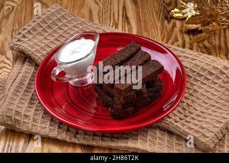 Croûtons frits avec sauce à la crème aigre garlick sur une assiette rouge.En-cas à la bière sur une table en bois. Banque D'Images