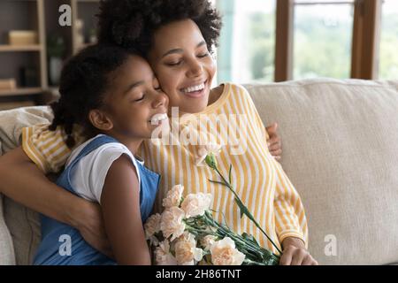 Bonne fille africaine paisible fille et mère embrassant sur le canapé Banque D'Images