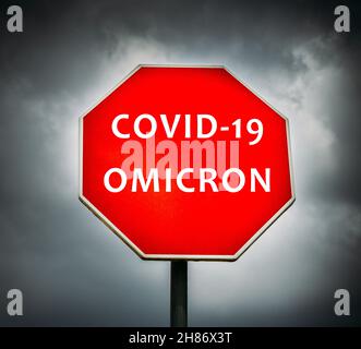 Covid-19 Omicron écrit sur le panneau stop avec des nuages orageux en arrière-plan Banque D'Images