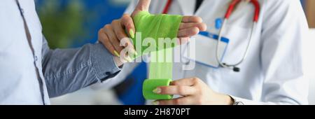 Médecin bandage de la plaie sur le bras du patient avec bandage vert en clinique de près Banque D'Images