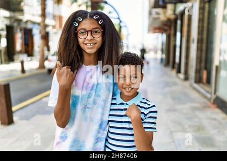 Famille afro-américaine de la peine et de la sœur debout dans la rue pointant du doigt à un soi souriant heureux et fier Banque D'Images