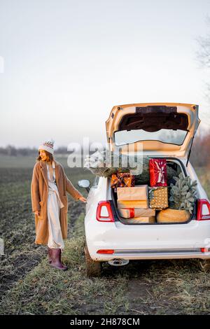 Femme et voiture pleine de boîtes-cadeaux du nouvel an Banque D'Images