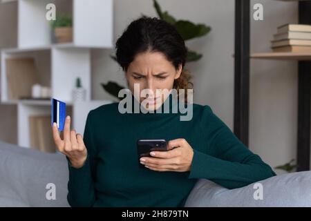 Femme inquiète regardant sur smartphone ayant des finances volées de la carte Banque D'Images