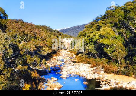 Barrage de Guthée sur la Snowy River dans les Snowy Mountains d'Australie - bois de gomme à neige à feuilles persistantes sur les pentes des chaînes avec des bouchons de neige en hiver. Banque D'Images