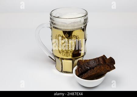 Une grande tasse de bière et des morceaux de pain sombre.Apéritif pour la bière, pain à l'ail et bière légère sur fond blanc. Banque D'Images