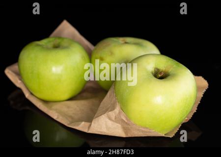 Trois pommes vert doux de Renet Simirenko sur papier brun, gros plan, isolées sur noir. Banque D'Images
