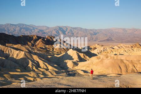 Parc national de Death Valley, Californie, États-Unis.Visiteur admirant la vue de Zabriskie point à travers le paysage aride du désert jusqu'à la chaîne Panamint, lever du soleil. Banque D'Images