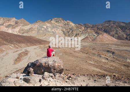 Parc national de Death Valley, Californie, États-Unis.Visiteur solitaire admirant la vue sur le paysage désertique aride jusqu'aux falaises colorées de la Palette de l'artiste. Banque D'Images