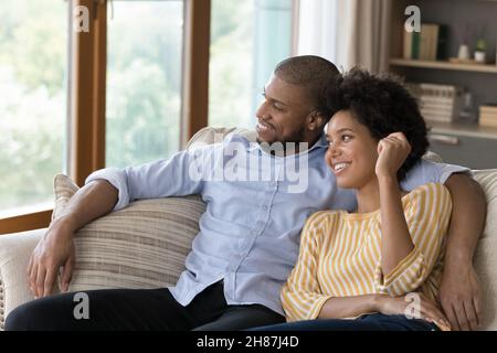 Joyeux jeune Noir couple marié se relaxant sur le canapé à la maison Banque D'Images