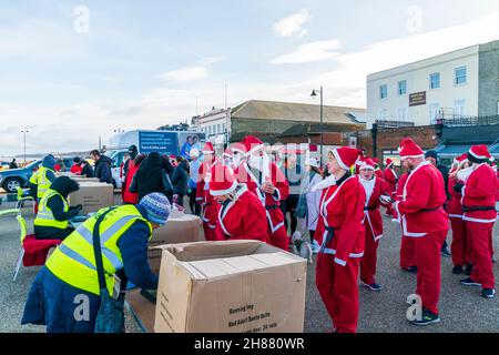 Des files d'attente, toutes habillées comme le Père Noël, font la queue pour s'inscrire à l'événement caritatif « Santa's on the Bay » organisé à l'aide des hospices Pilgrims sur le front de mer à Herne Bay, dans le Kent, le matin de fin novembre. Banque D'Images