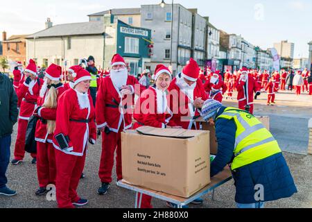 Des files d'attente, toutes habillées comme le Père Noël, font la queue pour s'inscrire à l'événement caritatif « Santa's on the Bay » organisé à l'aide des hospices Pilgrims sur le front de mer à Herne Bay, dans le Kent, le matin de fin novembre. Banque D'Images