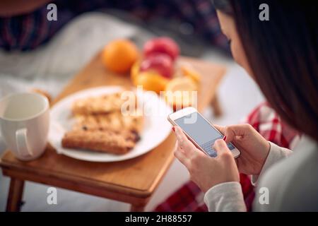 Jeune fille envoyant un message texte sur un téléphone portable le matin Banque D'Images