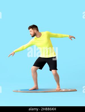 Bel homme barbu avec planche de surf sur fond bleu Banque D'Images