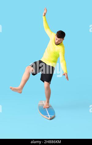 Bel homme barbu avec planche de surf sur fond bleu Banque D'Images