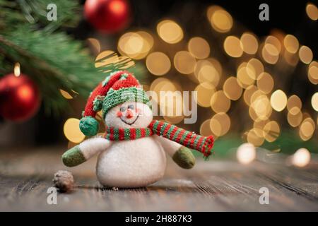 Bonhomme de neige jouet drôle sur le fond des lumières de Noël. Banque D'Images