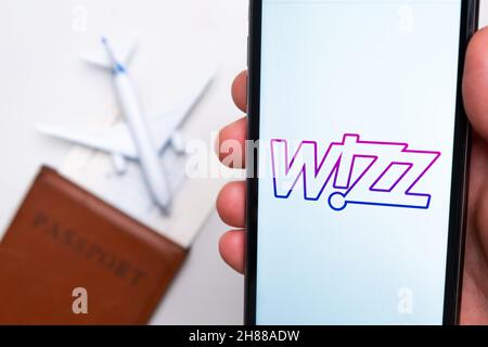 Application Wizz Airline sur un écran de smartphone avec un avion et un passeport en arrière-plan.Le concept de l'application Voyage.Novembre 2021, San Francisco, États-Unis Banque D'Images