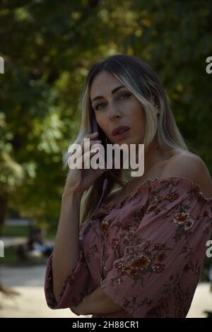 belle femme parlant avec intérêt au téléphone lors d'une journée ensoleillée en plein air hipster Banque D'Images