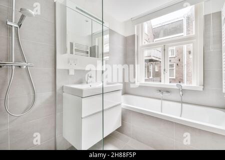 Décoration intérieure moderne, salle de bain lumineuse avec carrelage en céramique blanc et baignoire Banque D'Images