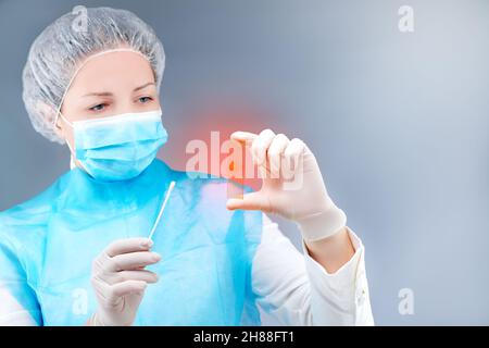 une jeune infirmière dans un masque médical pose devant la caméra sur un thème médical Banque D'Images