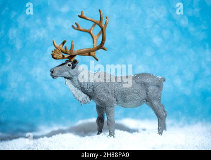 Miniature de Noël d'un cerf sur fond bleu brillant enneigé.Concept créatif de la nouvelle année Banque D'Images