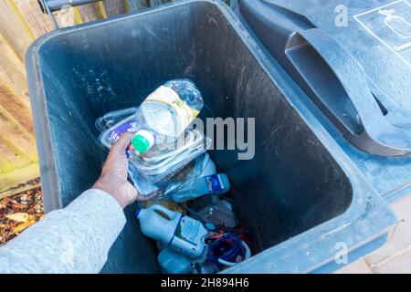 Un homme adulte dépose les articles en plastique dans un grand bac gris pour le recyclage Banque D'Images