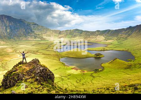 Le paysage de l'île de Corvo aux Açores avec l'homme sur le pic rocheux à bras ouverts.Concept de liberté et d'aventure de voyage. Banque D'Images