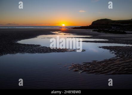 Coucher de soleil sur un ciel d'hiver clair à l'extrémité de la baie de Rhossili sur la péninsule de Gower à Swansea au Royaume-Uni Banque D'Images