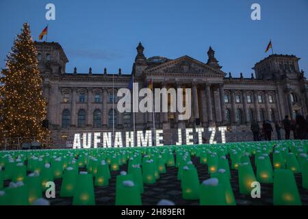 Berlin, Allemagne.28 novembre 2021.Feux verts devant le bâtiment Reichstag à Berlin, lieu de rencontre du Parlement allemand.Les résidents polonais près de la frontière biélorusse ont allumé des feux verts dans leurs maisons et leurs porches pour guider les migrants hors de la forêt et pour assurer leur sécurité.Manifestation à Berlin le 28 novembre 2021.(Credit image: © Michael Kuenne/PRESSCOV via ZUMA Press Wire) Banque D'Images