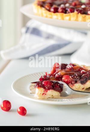 Gros plan d'un morceau de tarte aux canneberges avec la tarte complète derrière. Banque D'Images