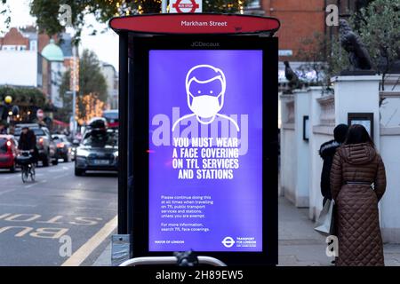 Londres, Royaume-Uni.28 novembre 2021.Un panneau est affiché à une gare routière qui indique « vous devez porter un visage couvrant les services et les gares de tfl » à Londres.Shoppers Profitez de Londres alors que la ville se met à l'honneur pour les fêtes de Noël avant le festival.À la lumière de la variante Covid Omicron, le transport pour Londres (tfl) a été vu exhortant les passagers à porter des masques.Crédit : SOPA Images Limited/Alamy Live News Banque D'Images