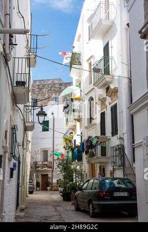 Monopoli, Italie - 20 août 2021 : allée caractéristique avec vêtements accrochés à la voiture sèche et garée dans le centre de Monopoli (Puglia) Banque D'Images