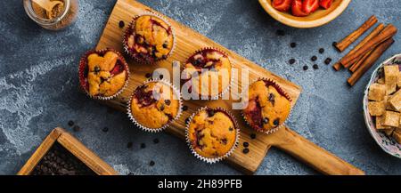 Muffins au chocolat aux fraises sur un vieux support en bois sur fond gris en béton.Vue de dessus. Banque D'Images