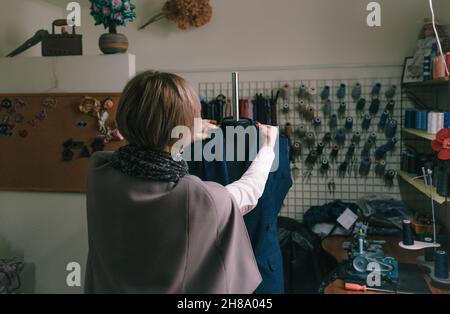 Une couturière féminine superpose manuellement un costume sur un mannequin dans un atelier de couture. Banque D'Images
