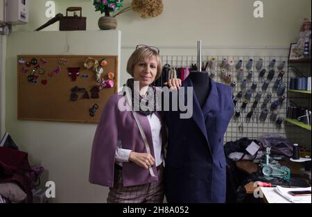 Une couturière féminine superpose manuellement un costume sur un mannequin dans un atelier de couture. Banque D'Images