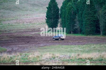 Véhicule tout-terrain Suzuki Jimny 4x4 bleu et argent, conduit autour d'une étendue boueuse dans les bois, Wiltshire, Royaume-Uni Banque D'Images