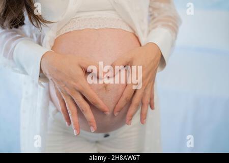 Crop femme enceinte touchant le ventre doucement dans la pièce Banque D'Images