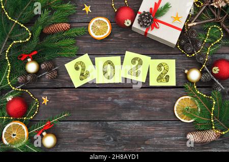 Bonne année 2022.Notes adhésives jaunes avec chiffres 2022 sur un fond en bois de fête avec espace de copie.Composition de pose plate avec boîte cadeau, soutien-gorge en sapin Banque D'Images