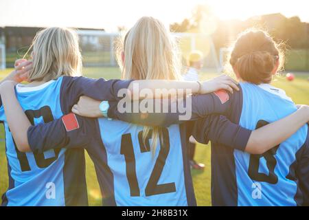 Royaume-Uni, vue arrière des joueuses de football qui s'embrassent sur le terrain Banque D'Images