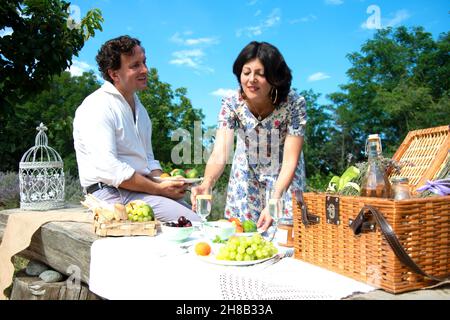 Couple d'âge mûr souriant, pique-nique dans le paysage Banque D'Images